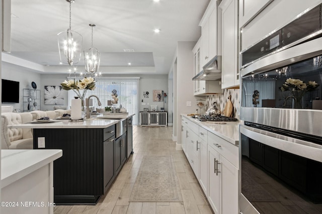 kitchen featuring a kitchen island with sink, white cabinetry, pendant lighting, and stainless steel appliances