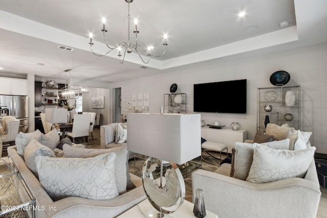 living room with an inviting chandelier and a tray ceiling