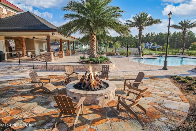 view of pool with a patio, pool water feature, ceiling fan, and a fire pit