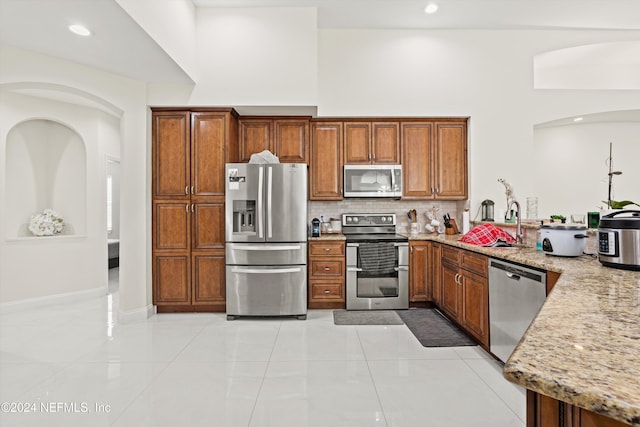 kitchen with light stone countertops, light tile patterned floors, and stainless steel appliances