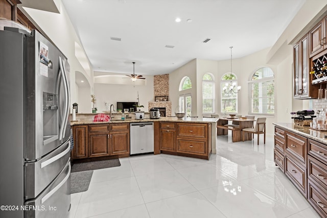 kitchen featuring kitchen peninsula, appliances with stainless steel finishes, light stone counters, and pendant lighting