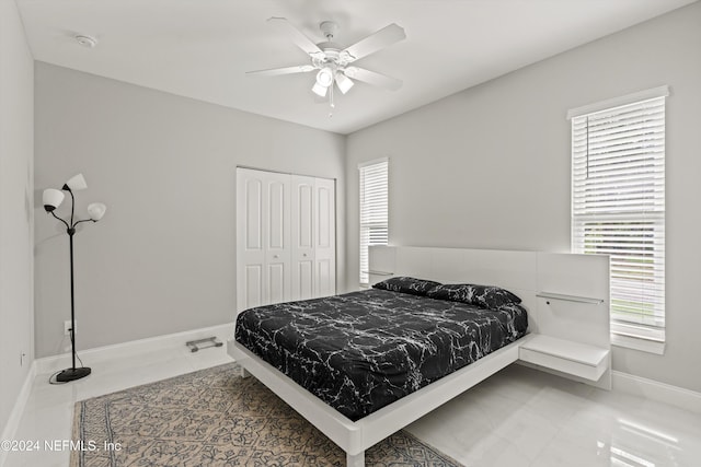 tiled bedroom with ceiling fan, a closet, and multiple windows