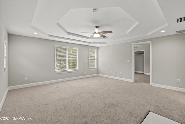 carpeted empty room with ceiling fan and a tray ceiling