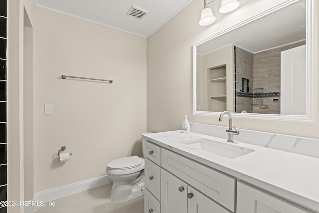 bathroom with a tile shower, vanity, and toilet