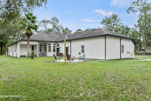 back of property featuring a patio area, a yard, and an outdoor fire pit