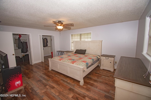 bedroom featuring a textured ceiling, two closets, ceiling fan, and dark hardwood / wood-style floors