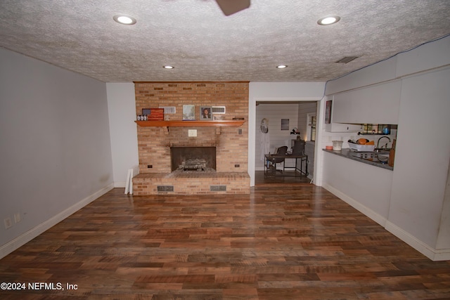 unfurnished living room with a fireplace, a textured ceiling, and dark hardwood / wood-style flooring