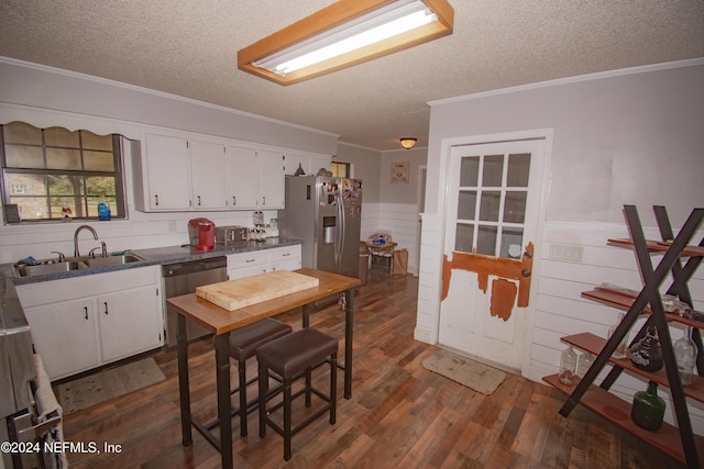 kitchen featuring appliances with stainless steel finishes, ornamental molding, dark wood-type flooring, sink, and white cabinetry