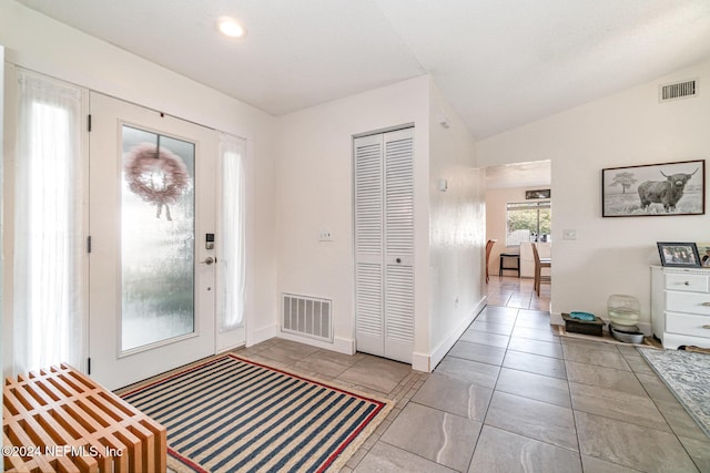 entryway featuring light tile patterned floors and vaulted ceiling