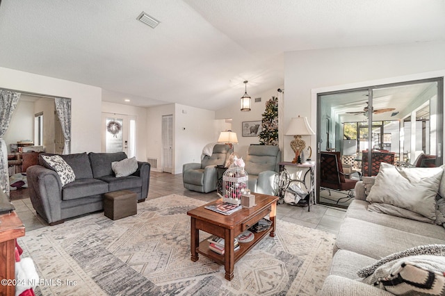 living room with ceiling fan, light tile patterned floors, and vaulted ceiling