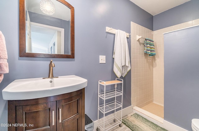 bathroom with a tile shower, vanity, and toilet