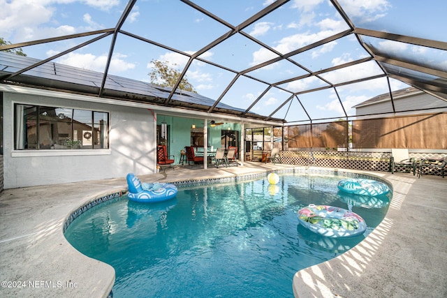 view of pool with a patio area, ceiling fan, and glass enclosure