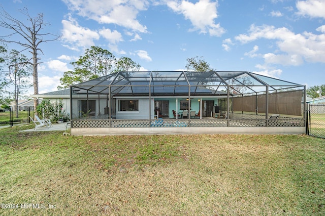 rear view of property featuring a lawn, glass enclosure, and a patio area