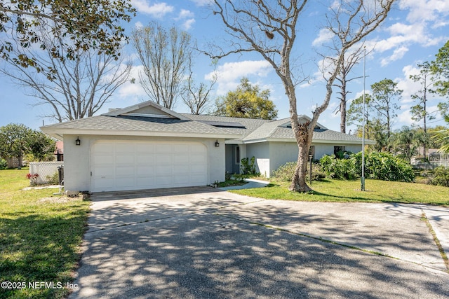 single story home featuring solar panels, an attached garage, a shingled roof, a front yard, and driveway