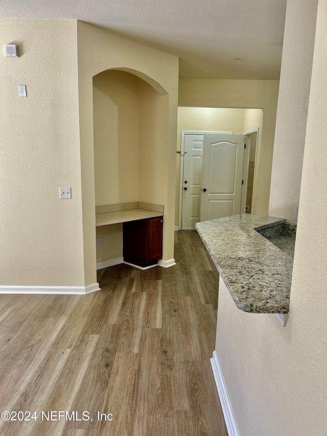 hall with light hardwood / wood-style floors and a textured ceiling