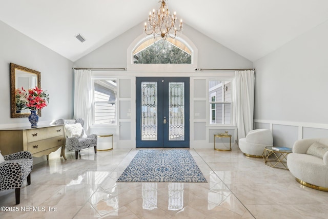 entryway with high vaulted ceiling, an inviting chandelier, and french doors