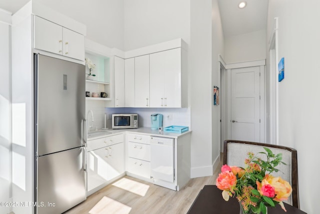 kitchen featuring appliances with stainless steel finishes, sink, backsplash, white cabinets, and light hardwood / wood-style floors