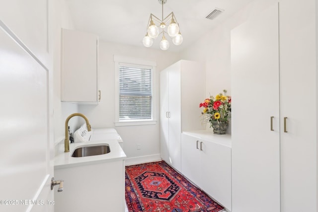 laundry room with sink, cabinets, and a chandelier