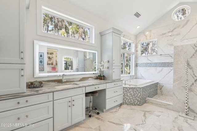 bathroom with vanity, vaulted ceiling, and a bathtub