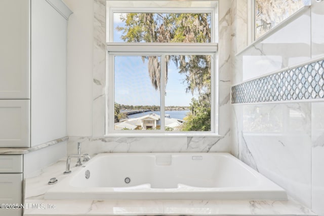 bathroom featuring tiled tub and a water view