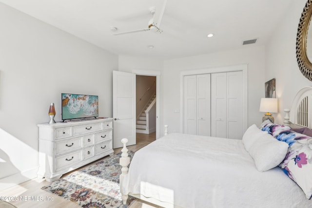 bedroom with light wood-type flooring, ceiling fan, and a closet