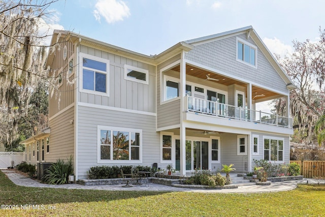 back of property with a balcony, a yard, and ceiling fan