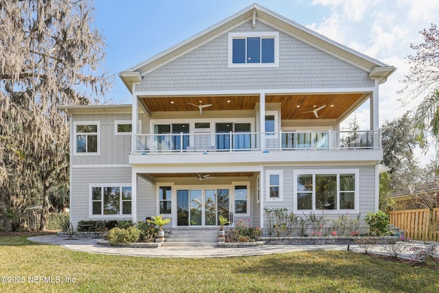 back of property with ceiling fan, a balcony, a patio area, and a lawn