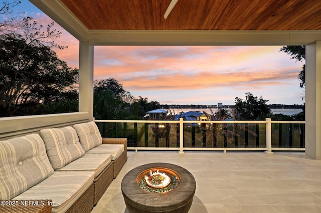 patio terrace at dusk with a water view and a fire pit