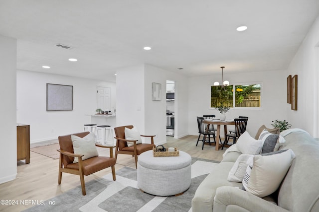 living room with light hardwood / wood-style floors and an inviting chandelier