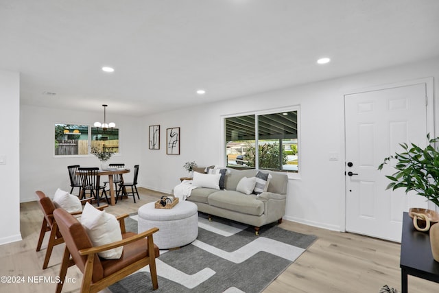 living room with light wood-type flooring, a healthy amount of sunlight, and a notable chandelier