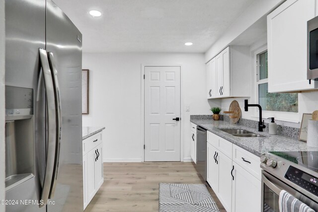 kitchen with light stone counters, light hardwood / wood-style floors, sink, and stainless steel appliances