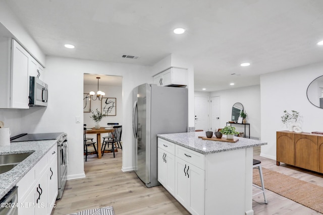 kitchen featuring light stone counters, white cabinets, light wood-type flooring, and appliances with stainless steel finishes