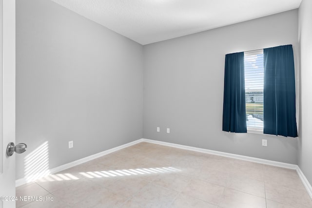 tiled spare room featuring a textured ceiling