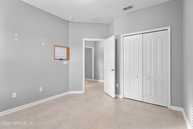 unfurnished bedroom with light tile patterned floors, a textured ceiling, and a closet