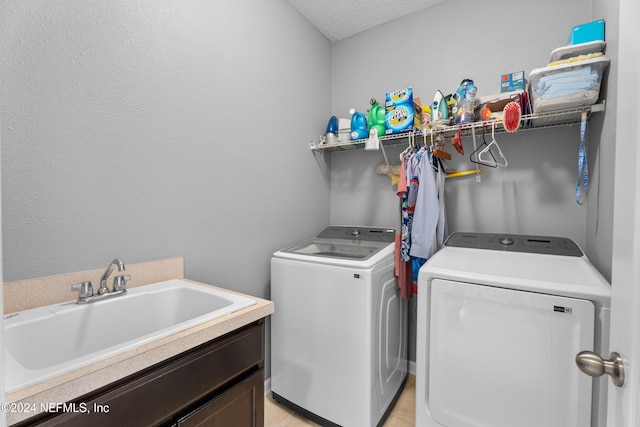 laundry room featuring cabinets, sink, washer and dryer, and a textured ceiling