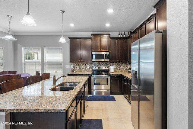 kitchen featuring ornamental molding, stainless steel appliances, a kitchen island with sink, sink, and hanging light fixtures