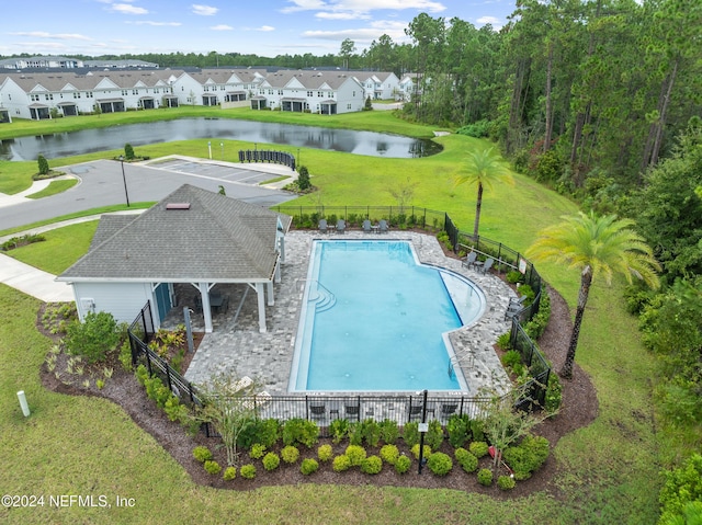 view of swimming pool featuring a patio area, a water view, and a yard