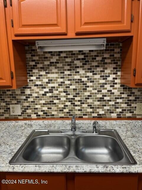 kitchen featuring tasteful backsplash, light stone counters, and sink