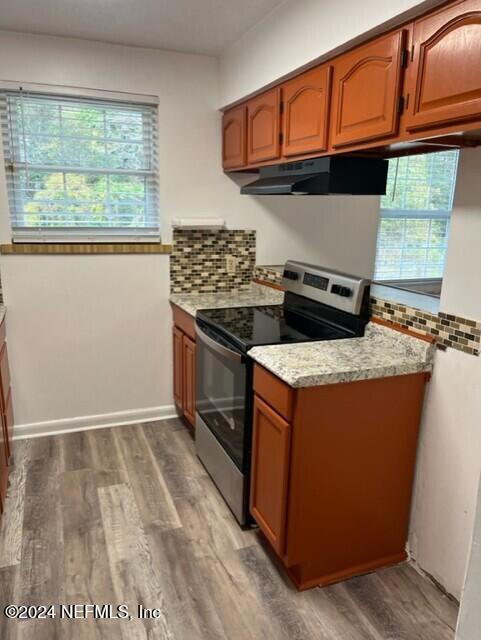 kitchen with a healthy amount of sunlight, wood-type flooring, and stainless steel range with electric cooktop