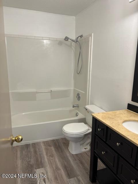 full bathroom with shower / bath combination, vanity, wood-type flooring, and toilet