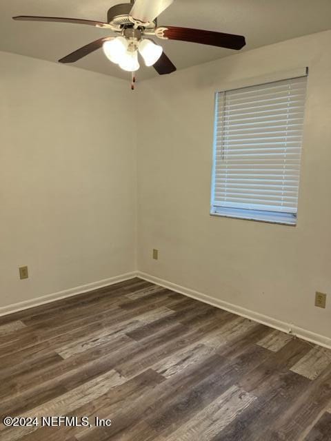 empty room with ceiling fan and dark hardwood / wood-style flooring