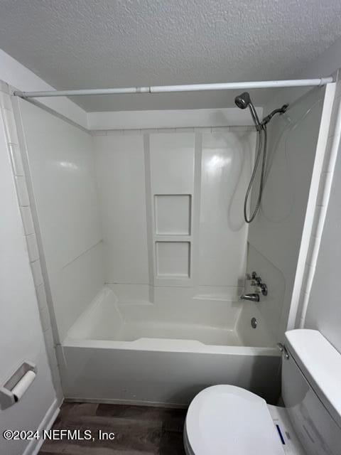 bathroom with hardwood / wood-style floors, shower / bath combination, a textured ceiling, and toilet