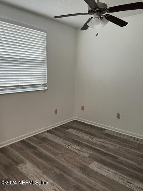 empty room with dark hardwood / wood-style floors and ceiling fan