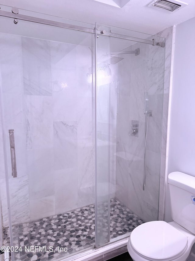 bathroom with toilet and a shower with shower door