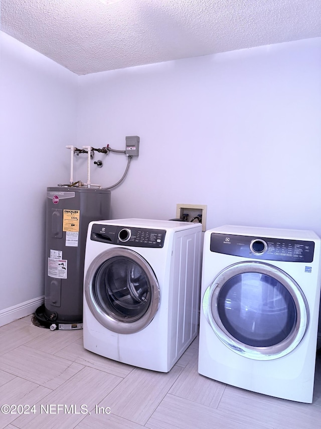 laundry room with washing machine and dryer, electric water heater, and a textured ceiling