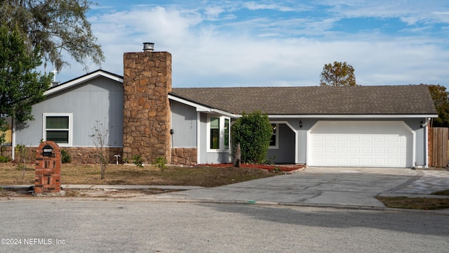 view of front of property featuring roof with shingles, a garage, driveway, and a chimney