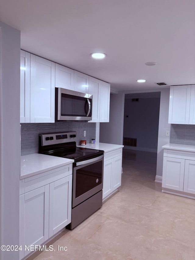 kitchen with decorative backsplash, white cabinetry, light tile patterned flooring, and stainless steel appliances