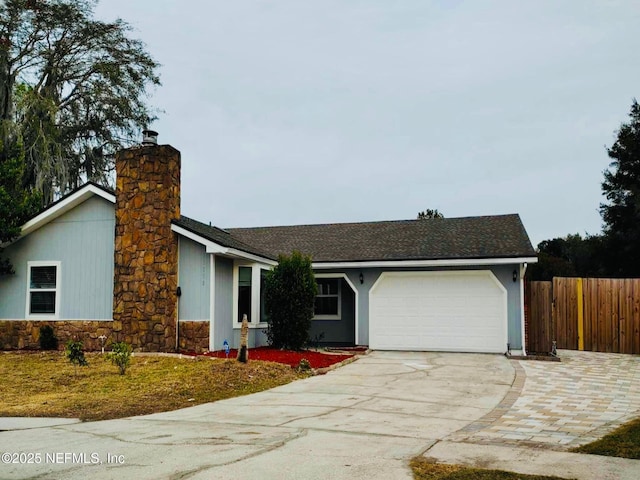 view of front of home with a chimney, concrete driveway, an attached garage, and fence