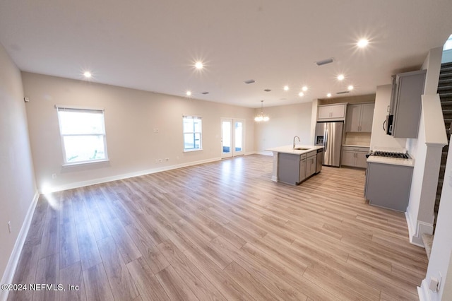 kitchen with a wealth of natural light, stainless steel appliances, a kitchen island with sink, and light hardwood / wood-style floors