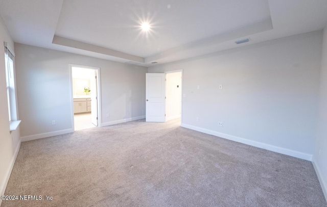 carpeted spare room with a raised ceiling